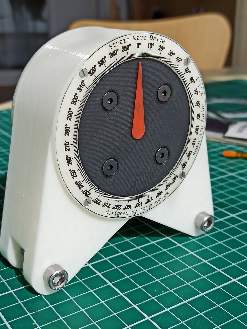 3D-printed strain-wave drive demonstrator with an orange pointer on a printed reduction-ratio dial